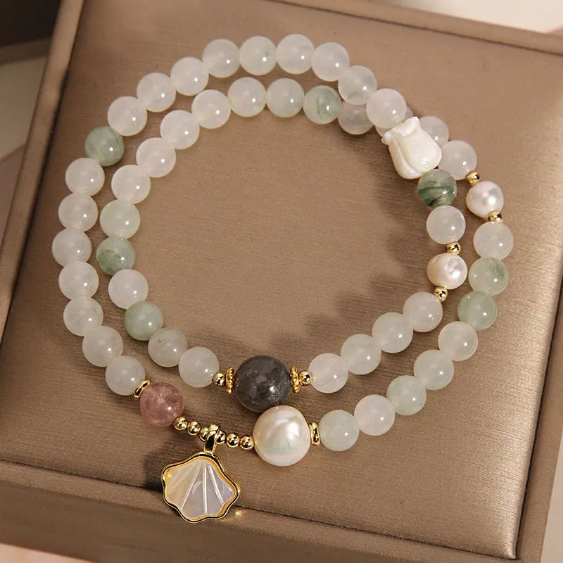Women's crystal bracelet with a carved jade shell ginkgo leaf pendant on a gold-plated setting.