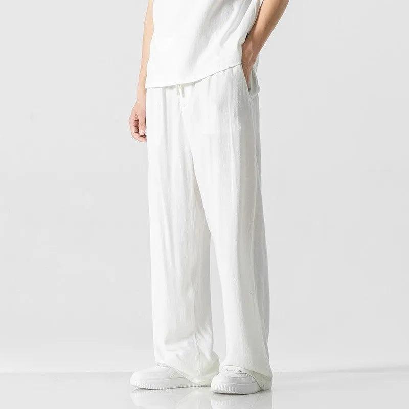 Man modelling beige linen drawstring trousers with a straight-leg cropped fit.