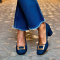 Dark blue suede women's square toe pumps with low top and short heel on a white background