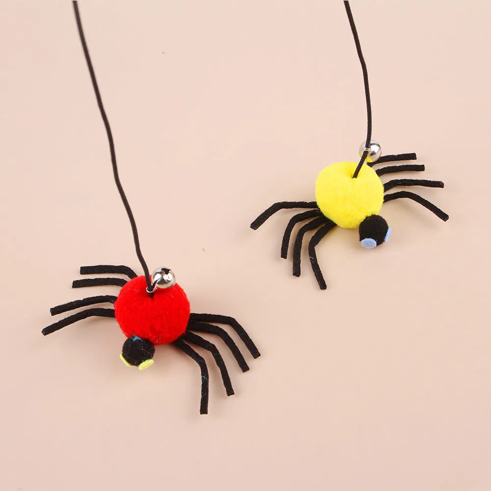 Red hanging cat toy with feather wand, bells, and spider on elastic rope, mounted on a door.
