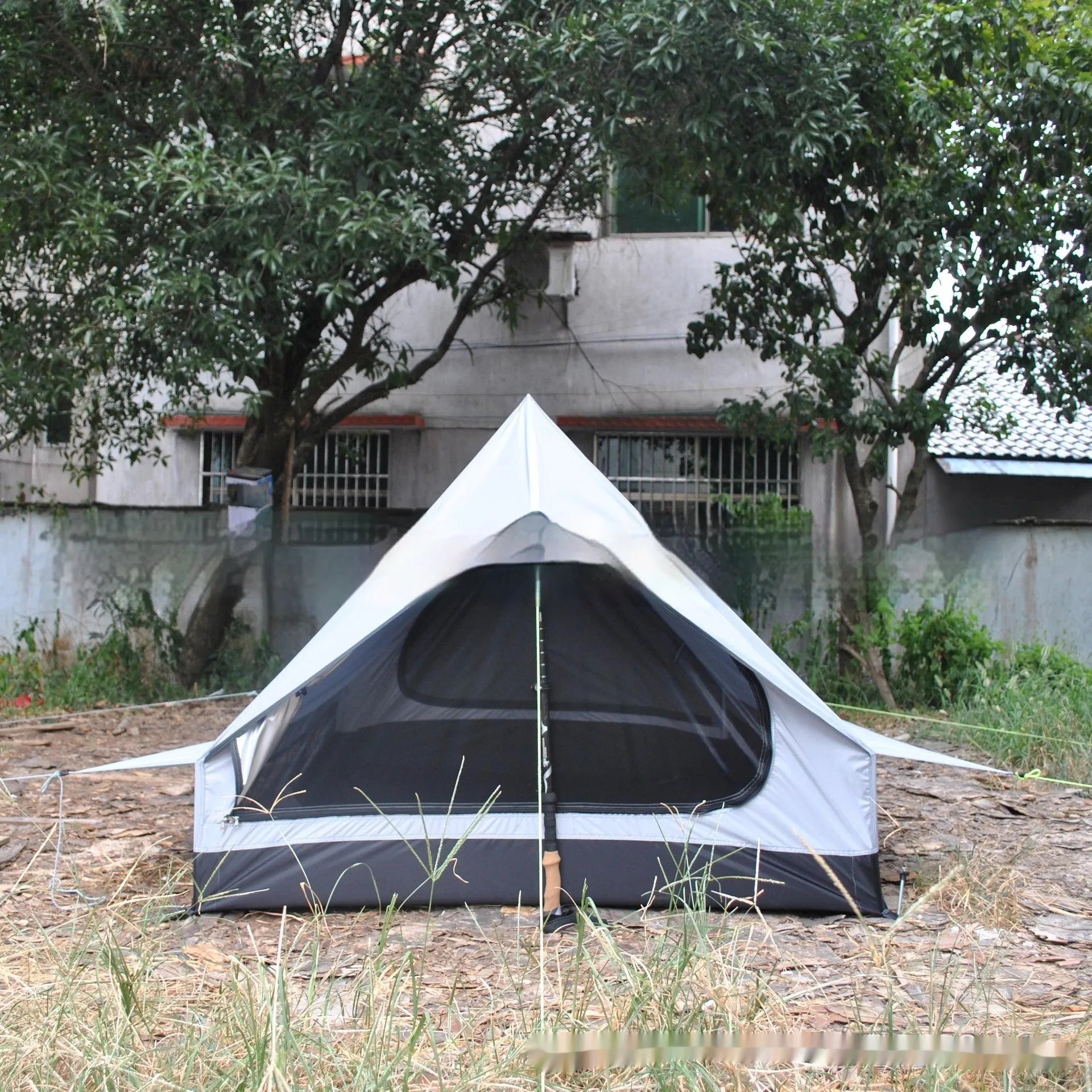 Brown or white A-frame pole-free cabin tent erected with hiking cane supports