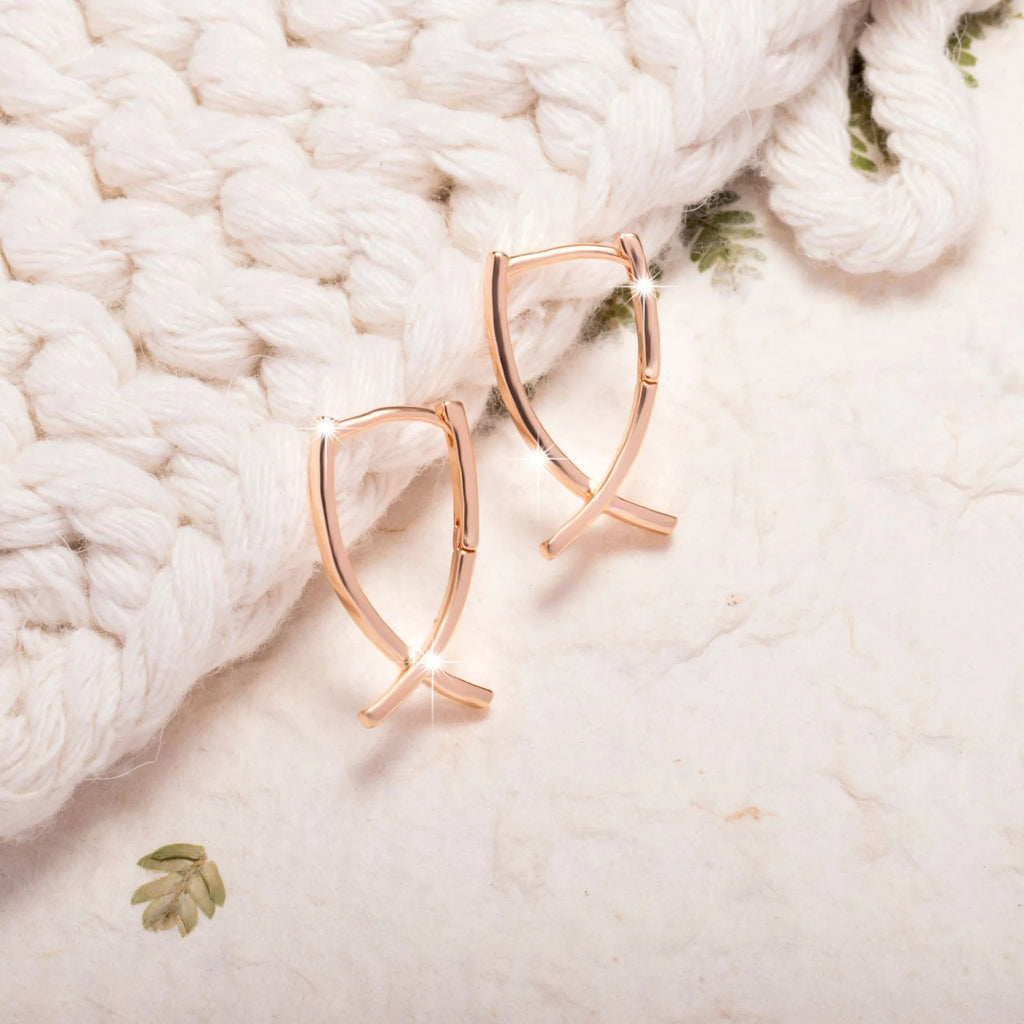 Rose gold coloured cross shaped earrings on a copper base.