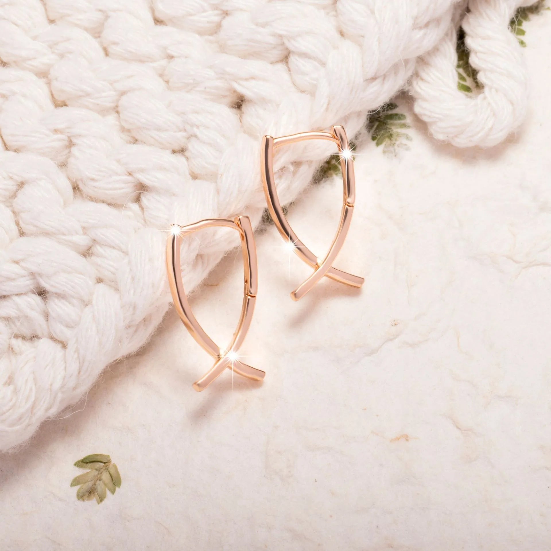 Rose gold coloured cross shaped earrings on a copper base.