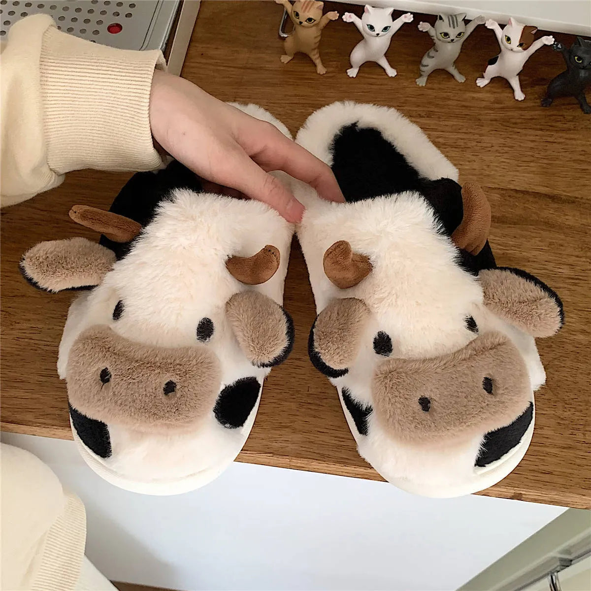 White cartoon cow plush slippers for women with a textured anti-slip sole.