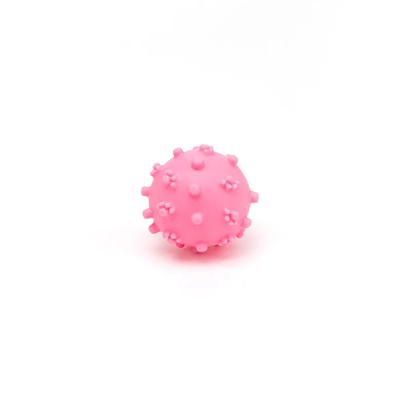 Bright blue, green, pink, and yellow spiked dog balls with paw print dimples on a white background.