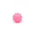 Bright blue, green, pink, and yellow spiked dog balls with paw print dimples on a white background.