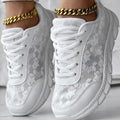 Women's white canvas running shoes with flat heel and round toe, showing sports style and lace-up design