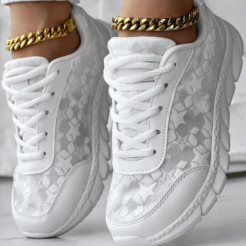 Women's white canvas running shoes with flat heel and round toe, showing sports style and lace-up design