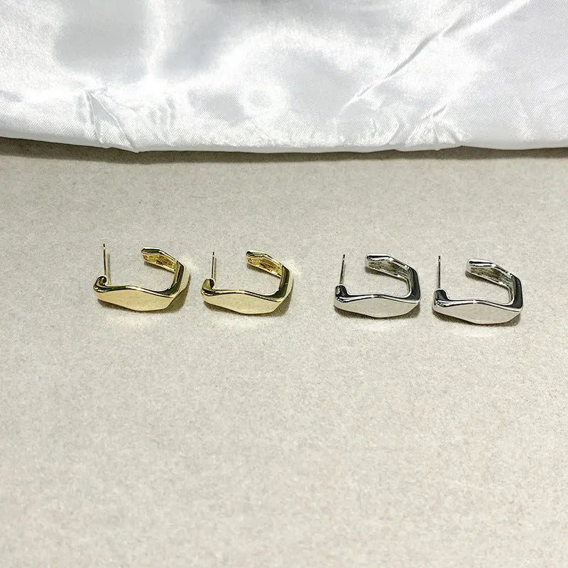 Irregular C-shaped metal stud earrings in Gold finish, minimalist design for everyday wear.
