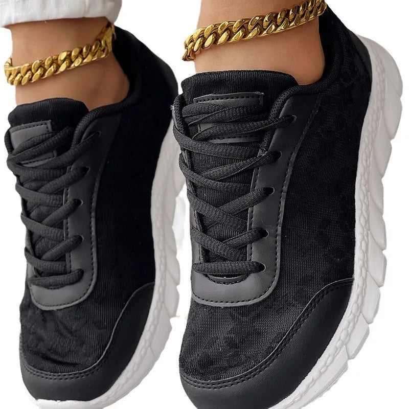 Women's white canvas running shoes with flat heel and round toe, showing sports style and lace-up design