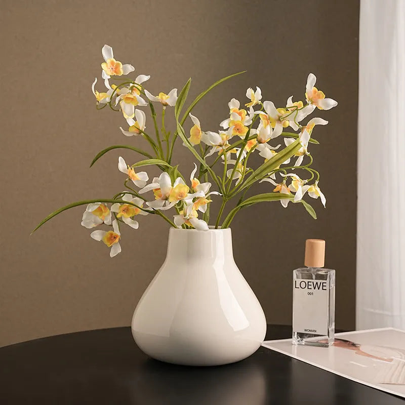 Ceramic round belly vase with coloured glaze finish in black or white, shown with artificial orchid stems