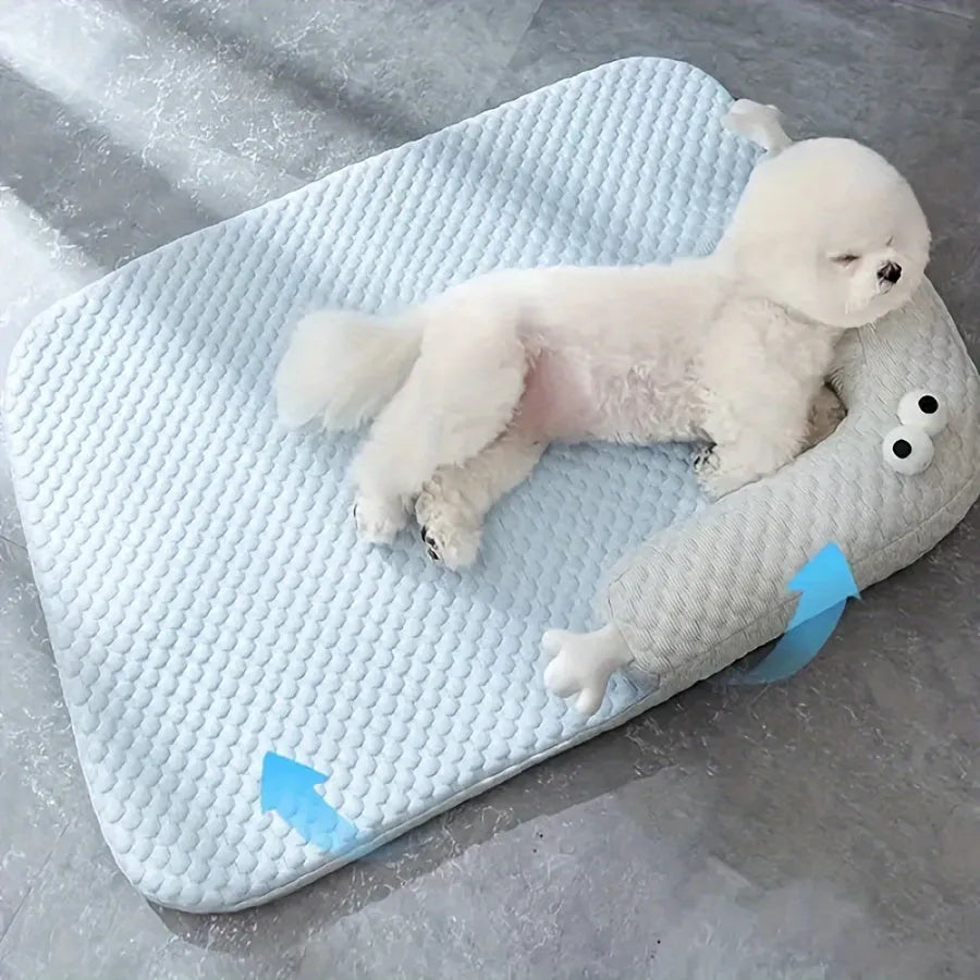 Blue pet bed with big-eyed monster design on a wooden floor next to a cat.