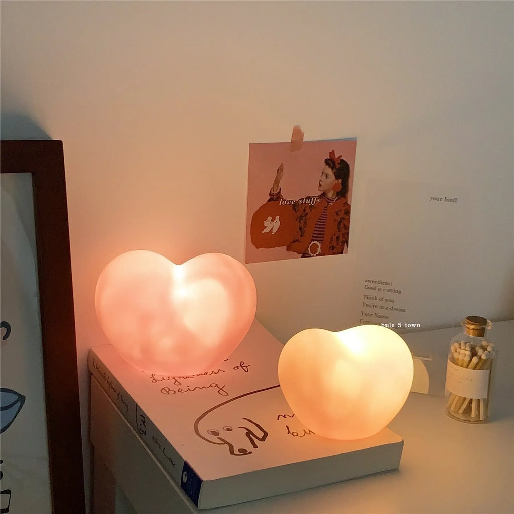 Pink and white vinyl atmosphere desk lamps in small and large sizes with warm LED glow.