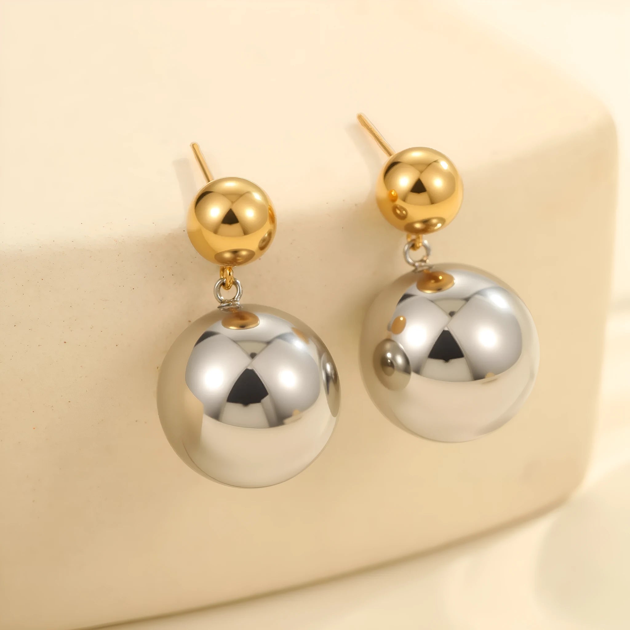 A pair of geometric round bead ear studs with a colour-block finish on stainless steel.