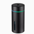Black aluminium car humidifier and essential oil diffuser with night light on a desk next to USB cable.