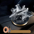 Silver solar powered rotating fighter plane air freshener ornament on a car dashboard.