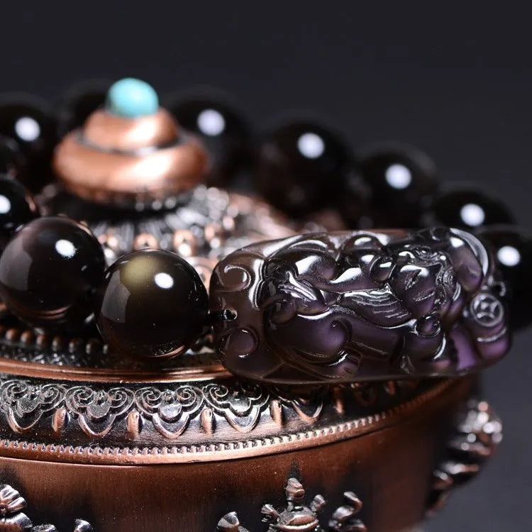 Polished icy obsidian crystal Pi Xiu bracelet with geometric ethnic style on adjustable cord.