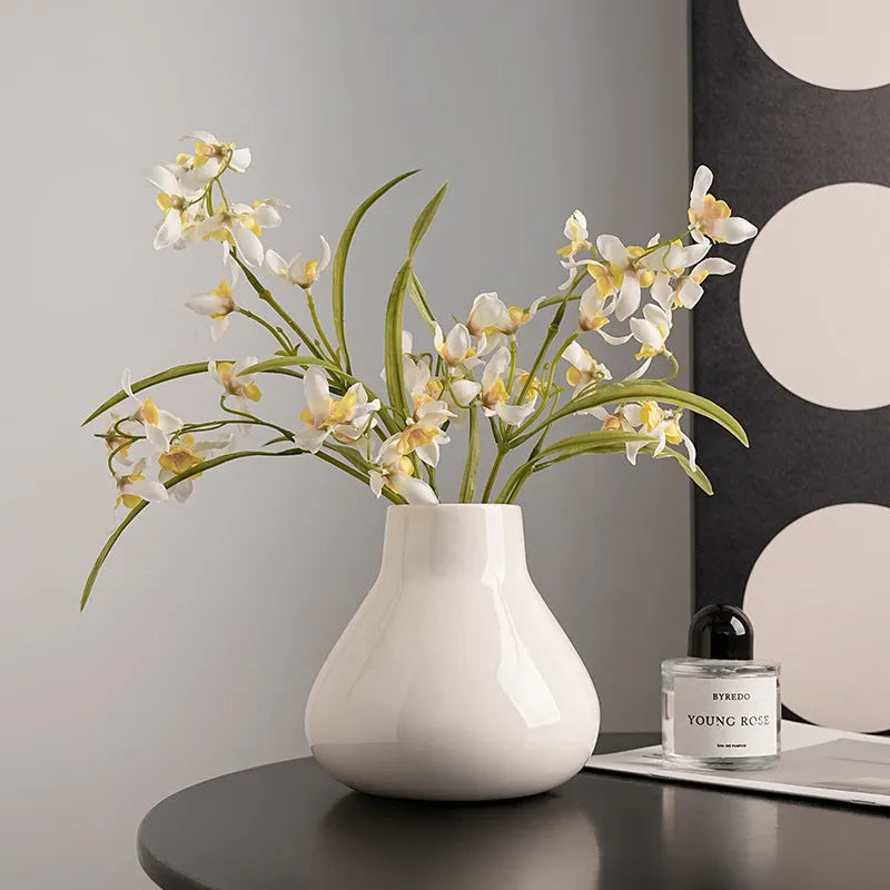 Ceramic round belly vase with coloured glaze finish in black or white, shown with artificial orchid stems