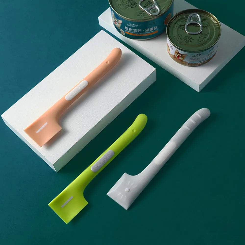 Long green handled pet food scoop next to a dog food tin, showing its right-angle scraping head.