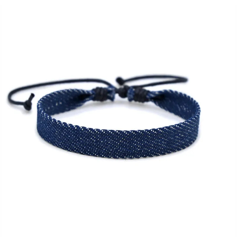 Handmade denim fabric bracelet carrying strap in national style on wrist, showing charm attachment point.