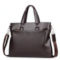 Black PU leather men's shoulder messenger bag with splicing style, shown next to a laptop