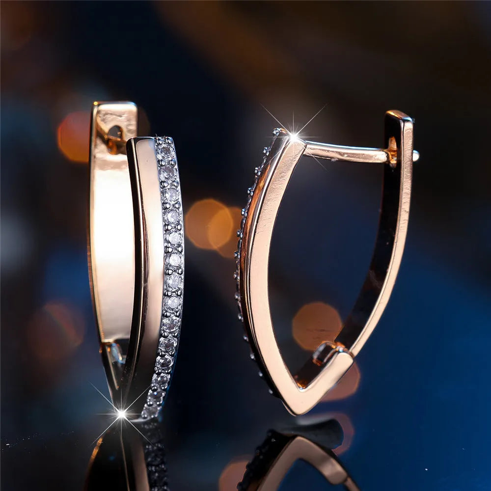 Geometric V-shaped women's earrings in champagne gold with white diamond accents on a copper base.