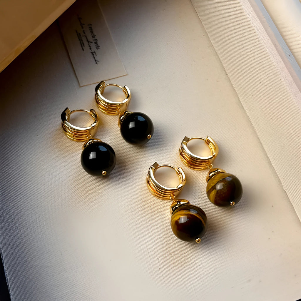 A pair of Fashion Maillard Tigereye earrings with a geometric shape and real gold plating, shown in brown and black colour options.