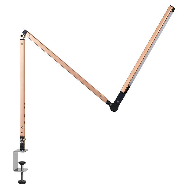 A black foldable LED desk lamp with a metal clip attached to a wooden desk edge, remote control nearby.
