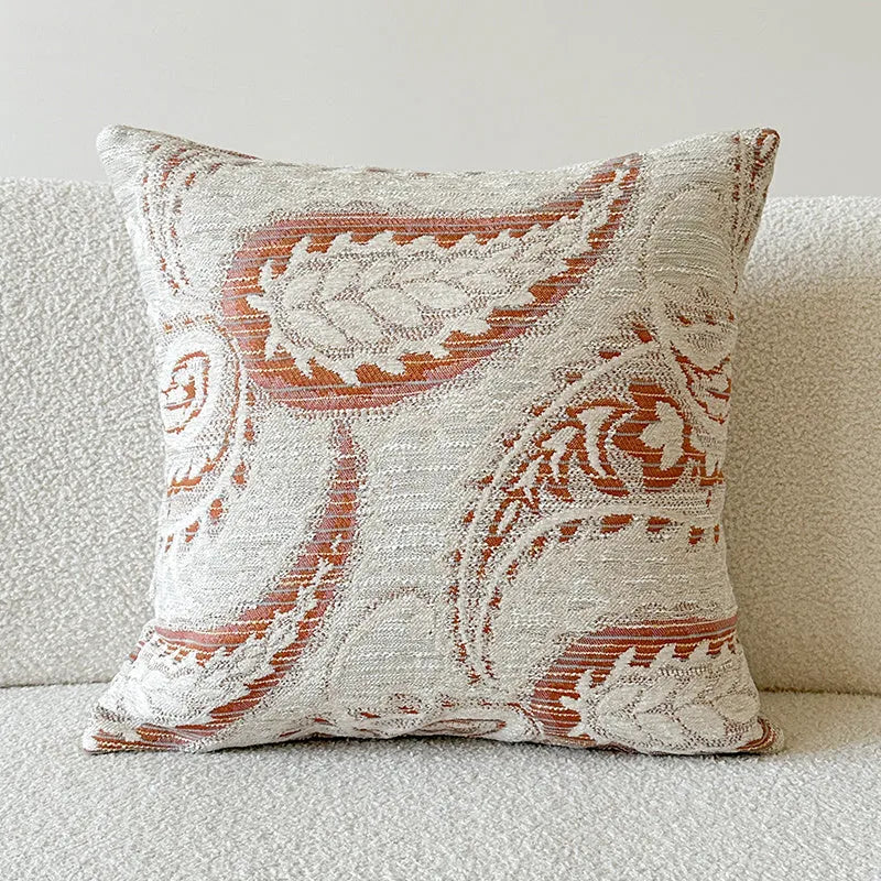 Amber paisley patterned jacquard sofa cushion cover on a sofa, showing textured fabric and plant motif.