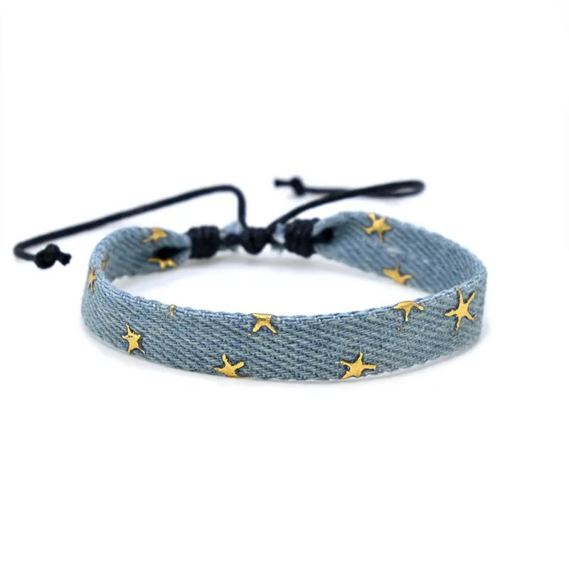 Handmade denim fabric bracelet carrying strap in national style on wrist, showing charm attachment point.