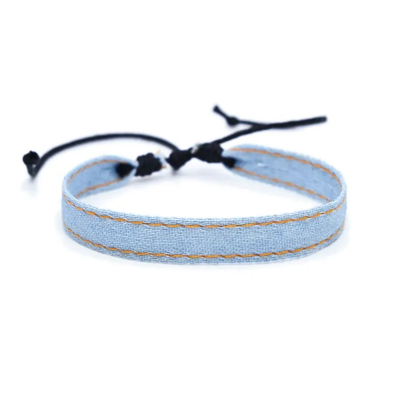 Handmade denim fabric bracelet carrying strap in national style on wrist, showing charm attachment point.