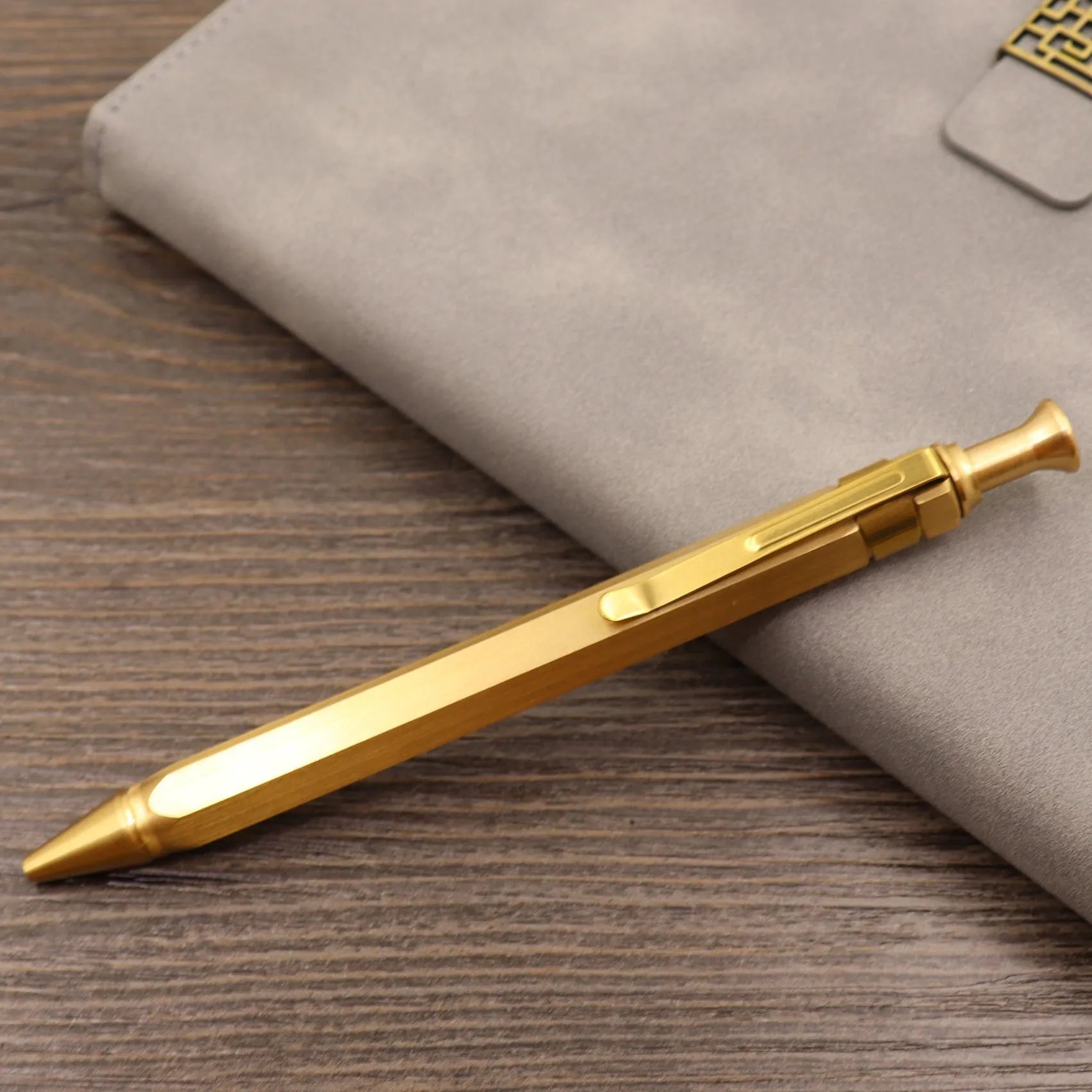 Solid brass cylindrical tactical pen with a press mechanism and six-ring detail.