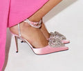 Women's black satin sandals with a heart-shaped rhinestone and pointed toe, showing the adjustable cross-strap fastening.