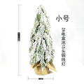 Small 24-inch artificial Christmas tree with snow sprayer finish and integrated lights on desktop