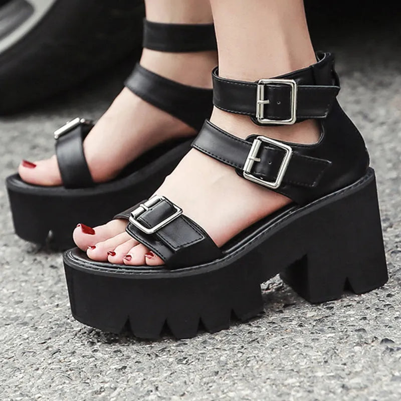 Black women's punk-style sandals with chunky heel, platform sole, buckle, and back zipper.