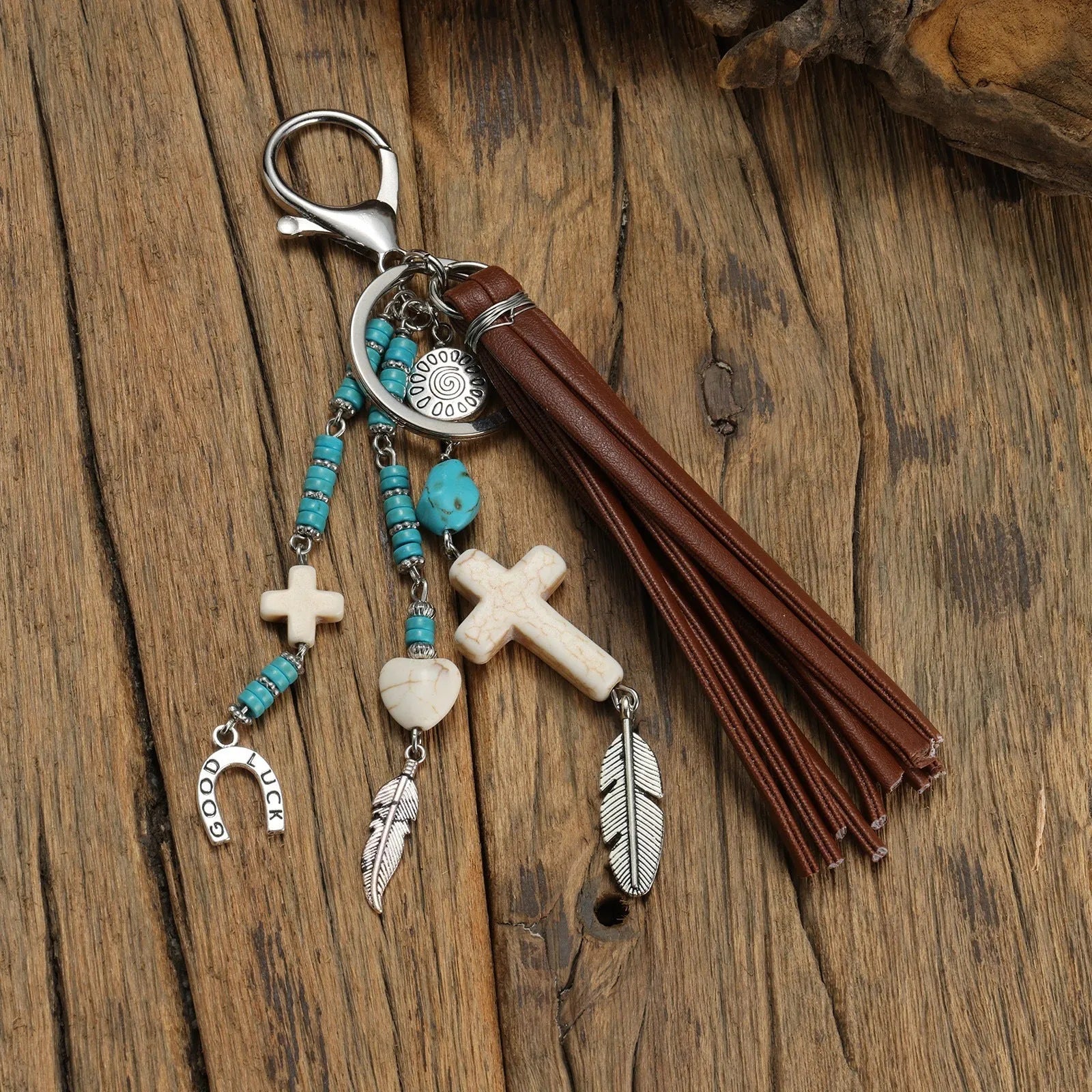 Alloy cross pendant keychain with leather rope and tassel in colour XY-3669 on a wooden surface