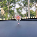 Blue plastic swing-shaped car decoration with a smiling face, hanging from a loop.