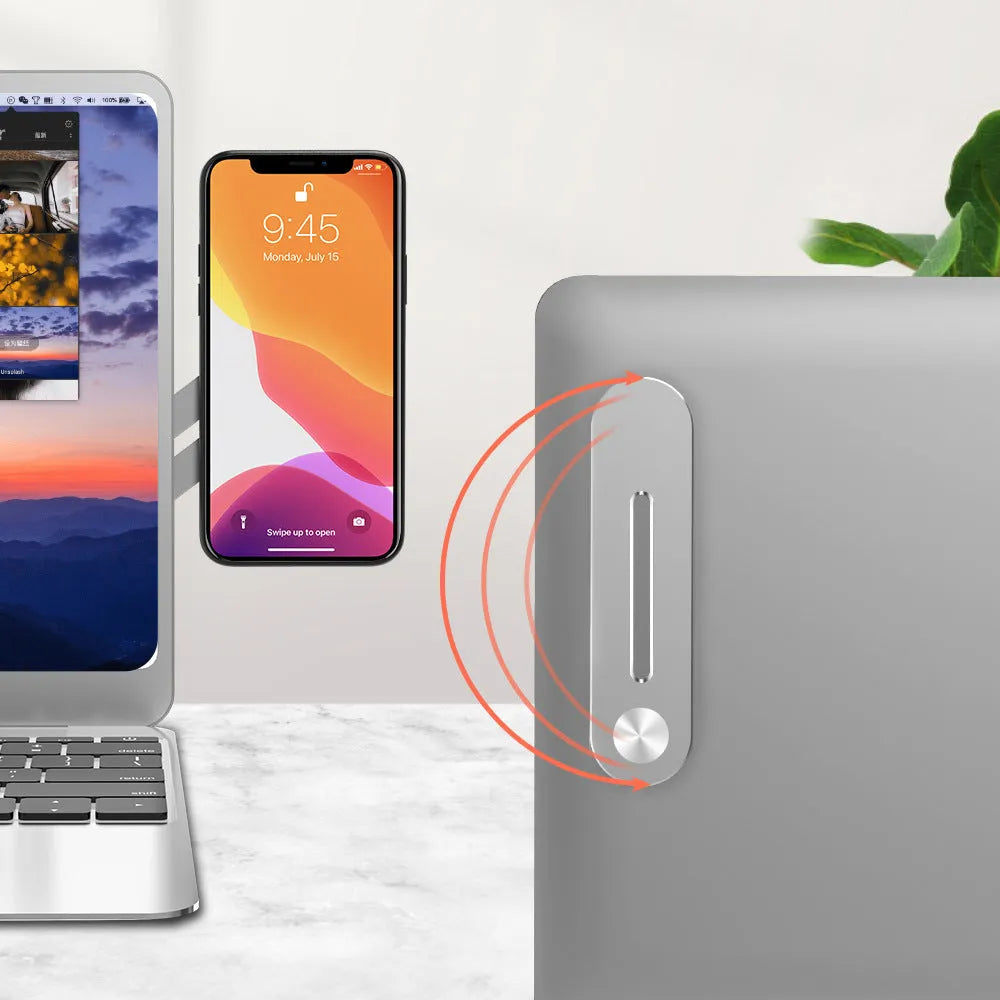 Silver aluminium bracket holding a mobile phone flush beside a laptop screen on a desk.