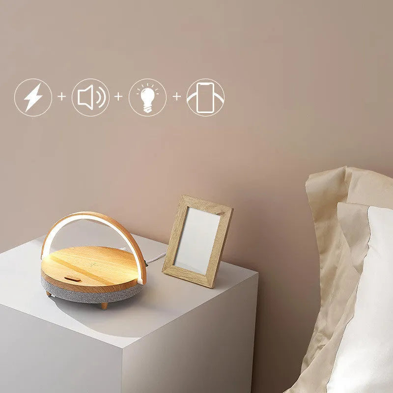 Wireless charging LED night light with Bluetooth speaker in marble pattern finish on a wooden table.