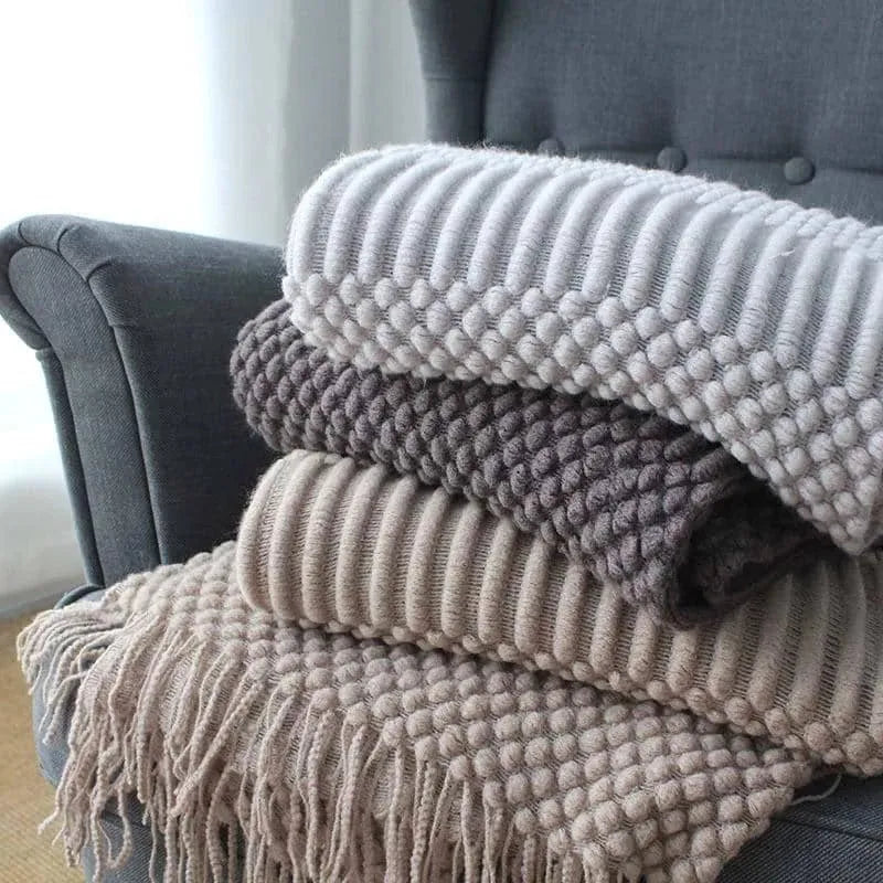 Small light grey polyester throw blanket folded on a sofa