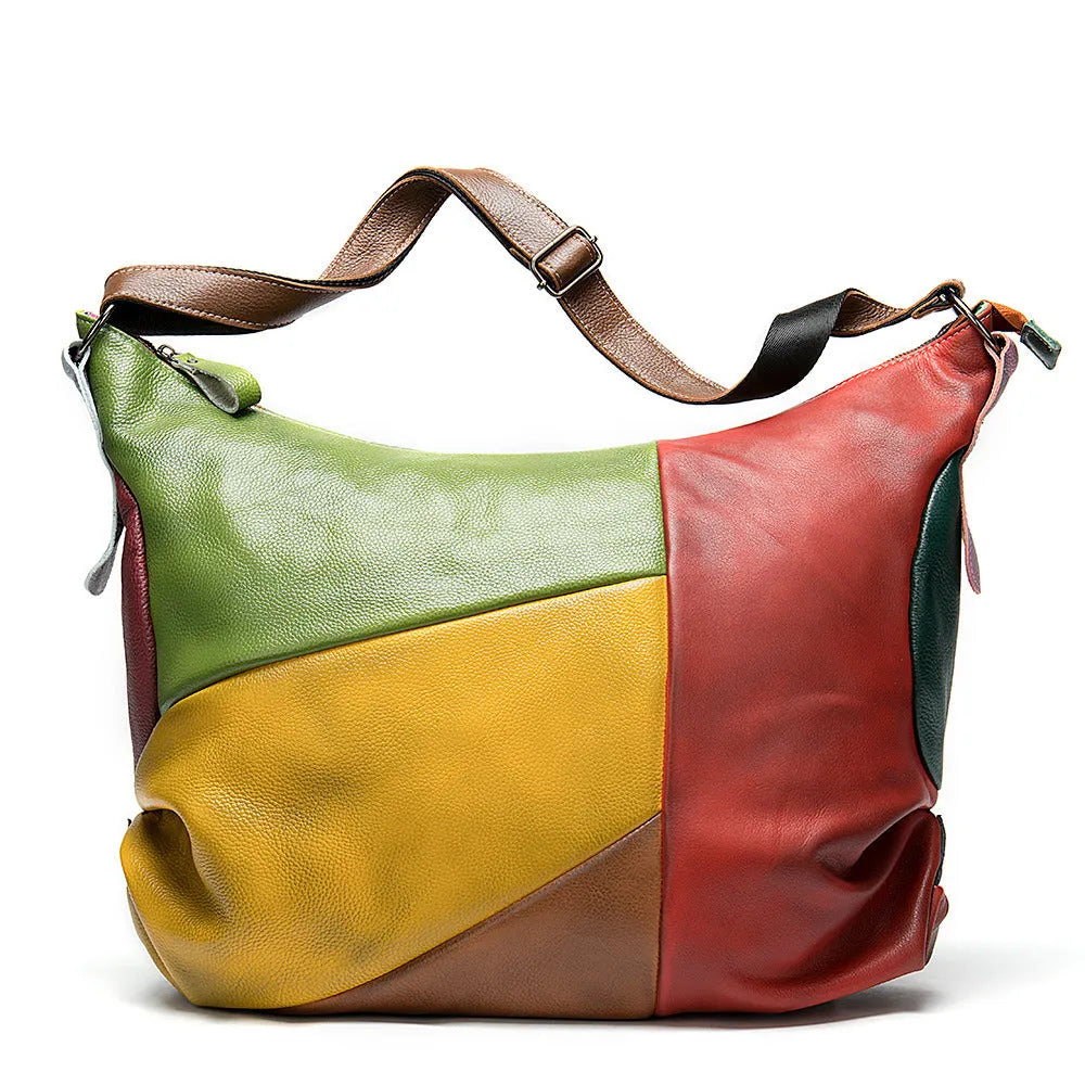 Brown cowhide leather crossbody travel bag showing front view with strap, holding a laptop and magazine.