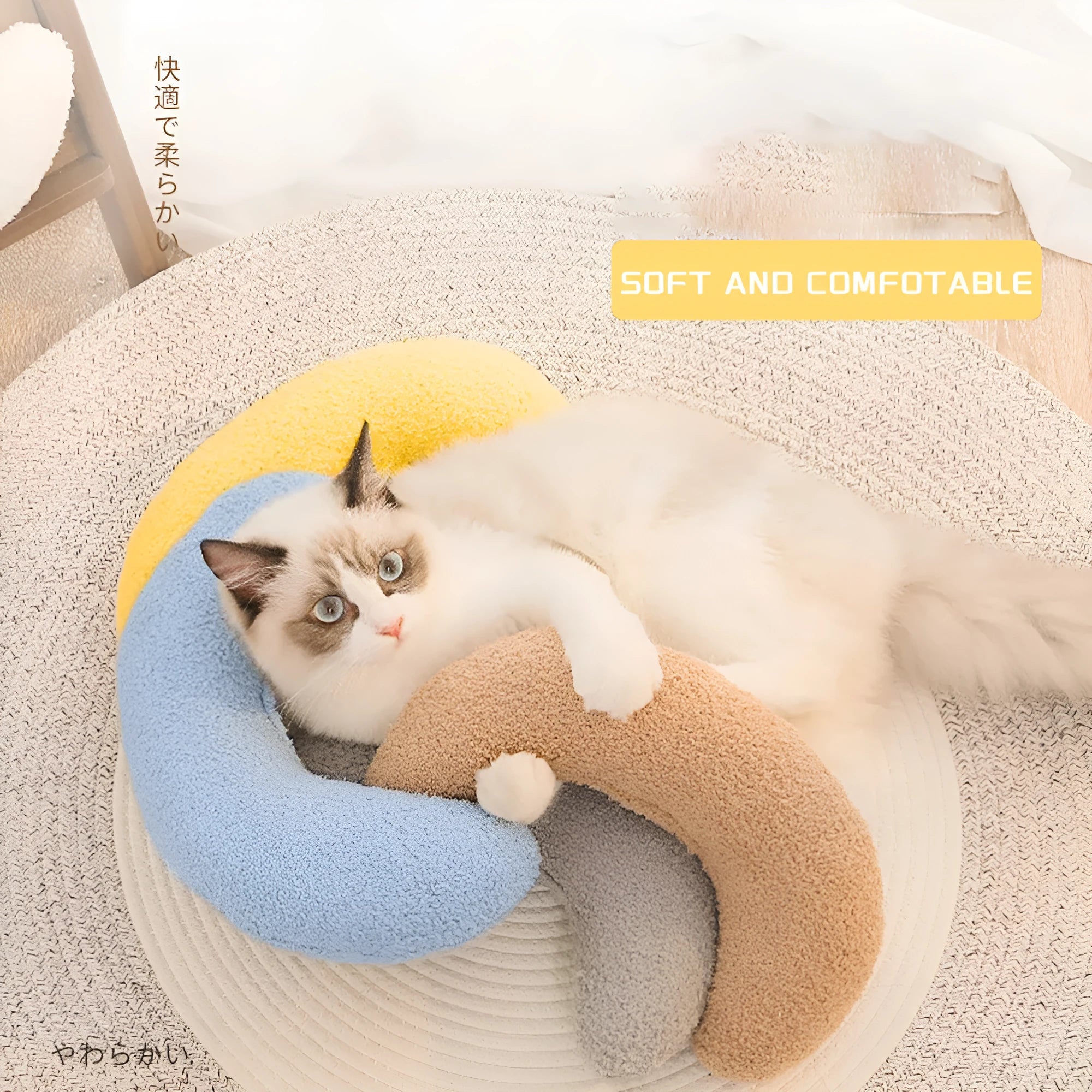 Blue U-shaped cat pillow with an adjustable fabric collar on a grey sofa.
