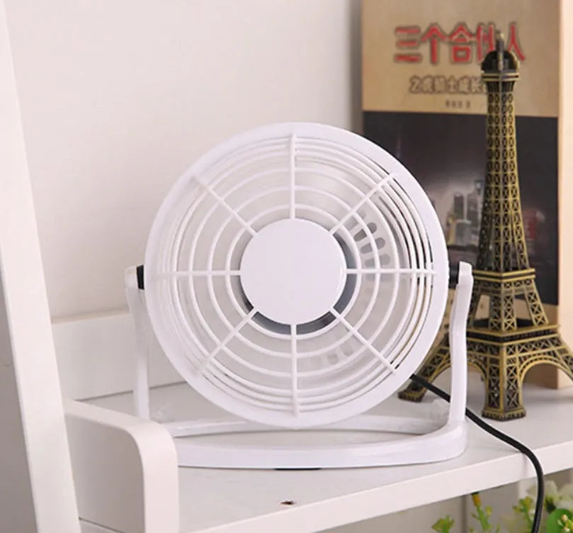 Black mini USB desktop fan with adjustable angle on wooden desk