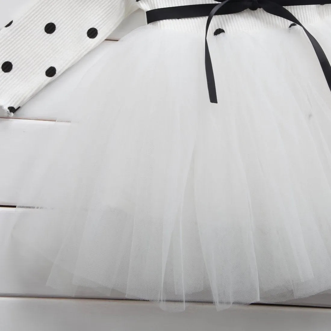 Baby girl in a long sleeve black tutu lace dress for a christening or birthday party.