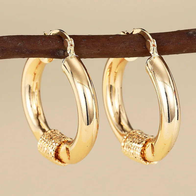 Geometric golden copper earrings with ear clip fastening showing ring and line design elements