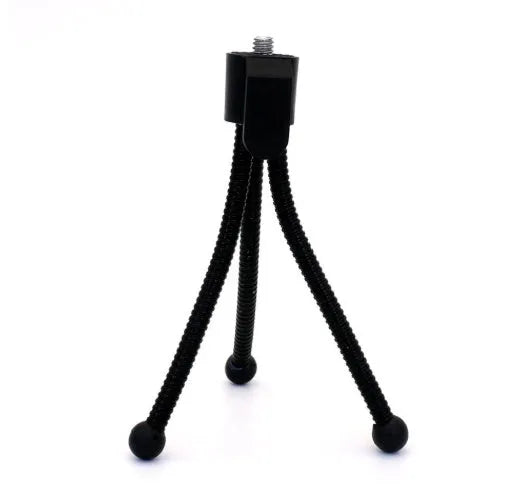 Small black iron mini tripod with ball head extended, next to an iPhone on a desk