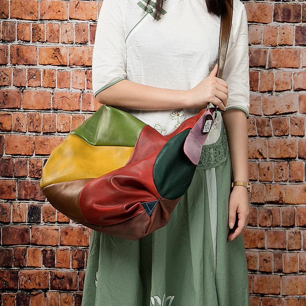 Brown cowhide leather crossbody travel bag showing front view with strap, holding a laptop and magazine.