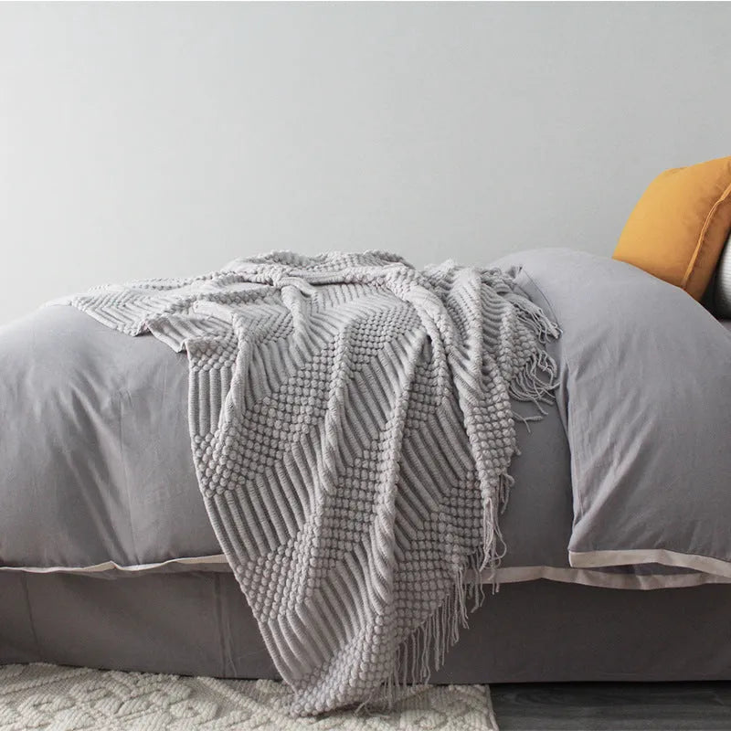Small light grey polyester throw blanket folded on a sofa