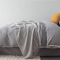 Small light grey polyester throw blanket folded on a sofa