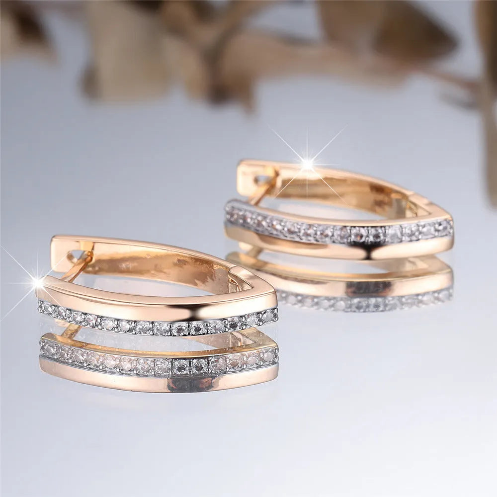 Geometric V-shaped women's earrings in champagne gold with white diamond accents on a copper base.